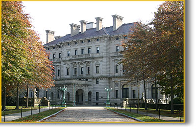 Entrance to large stone mansion with fall foliage along the drive at The Breakers