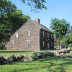 a New England salt box house with lawns and stone wall, birthplace of John Adams